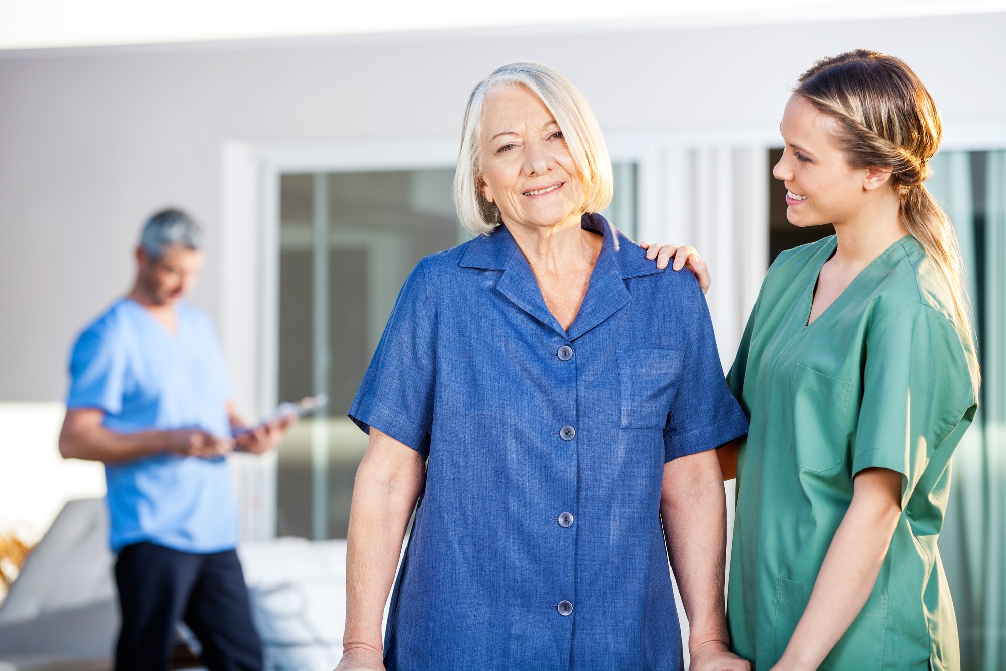 Portrait of smiling senior woman being assisted by female caretaker in nursing home